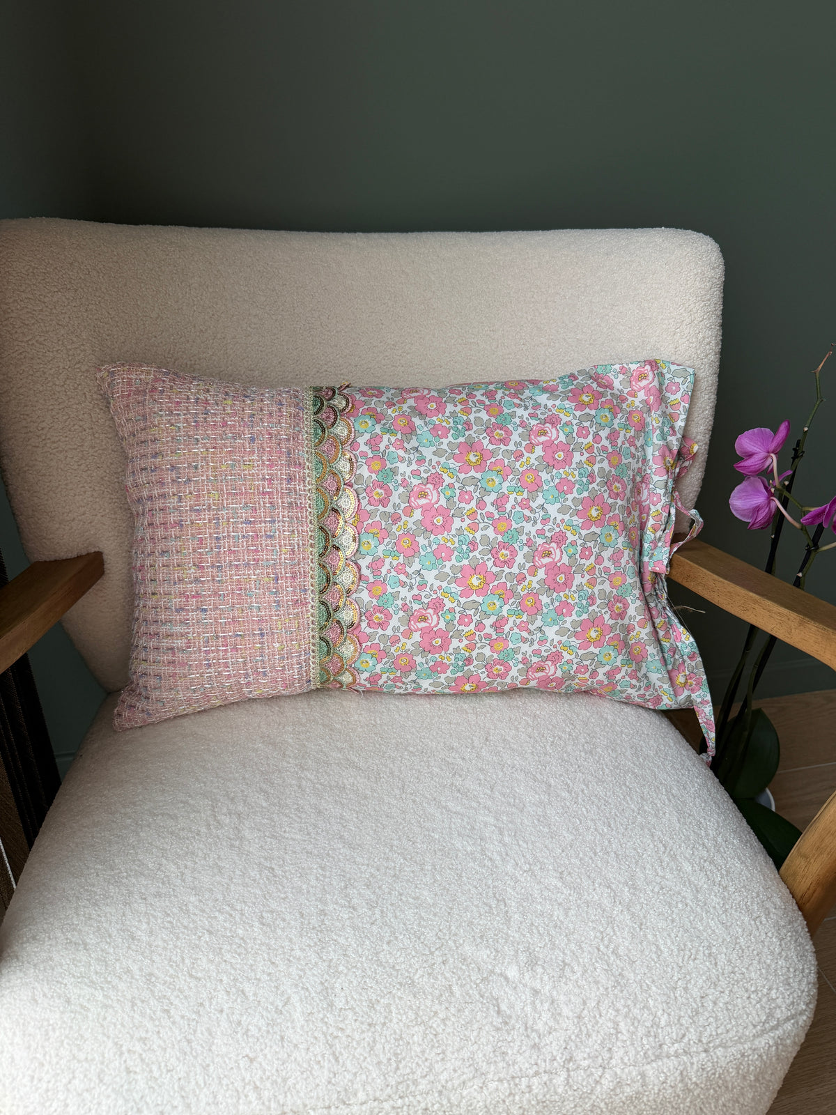 Verso du coussin en tweed rose et coton fleuri Liberty, séparés par un galon de dentelle festonné