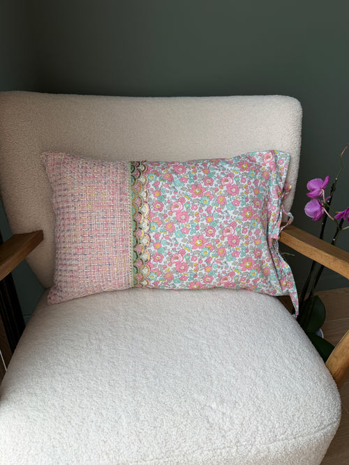 Verso du coussin en tweed rose et coton fleuri Liberty, séparés par un galon de dentelle festonné