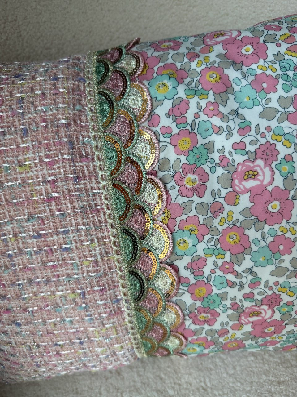 Détail du galon festonné à sequins entre le tweed rose et le coton Liberty du coussin, cousu main
