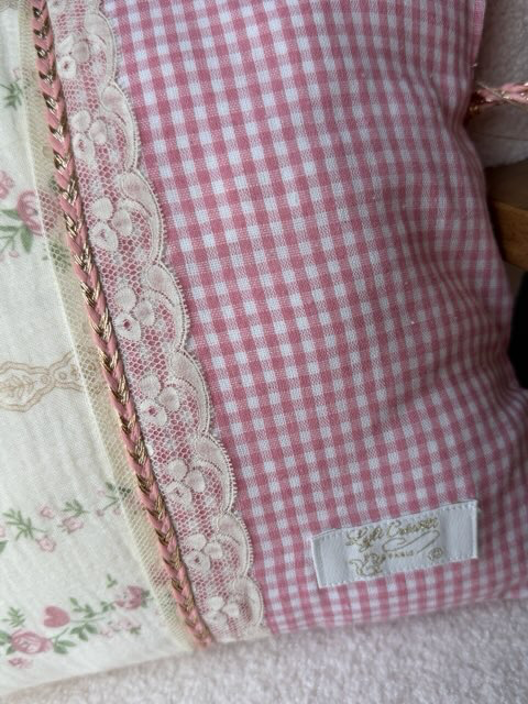 Zoom coussin fait main Lyli Créarti, jonction tissu floral vintage et vichy rose avec dentelle et galon torsadé doré et rose