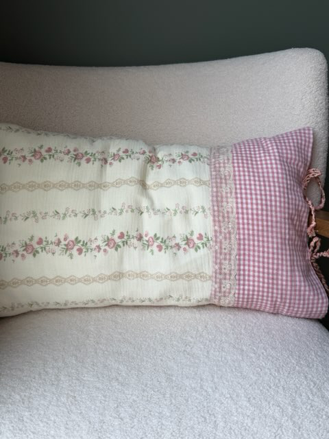 Coussin rectangulaire fait main Lyli Créarti, tissu à motif floral vintage rose sur fond ivoire et vichy rose, vue de dessus sur fauteuil en bouclette blanche