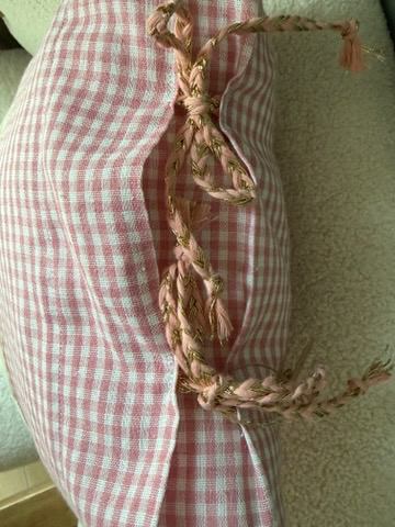 Détail coussin fait main Lyli Créarti, angle en vichy rose et blanc avec noeud en galon torsadé doré et rose
