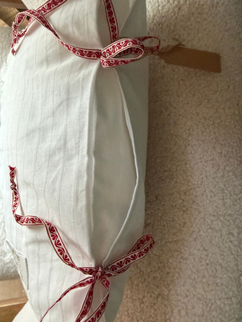 Côté coussin fait main en lin blanc rayé avec noeuds en ruban brodé motif folklorique rouge et blanc