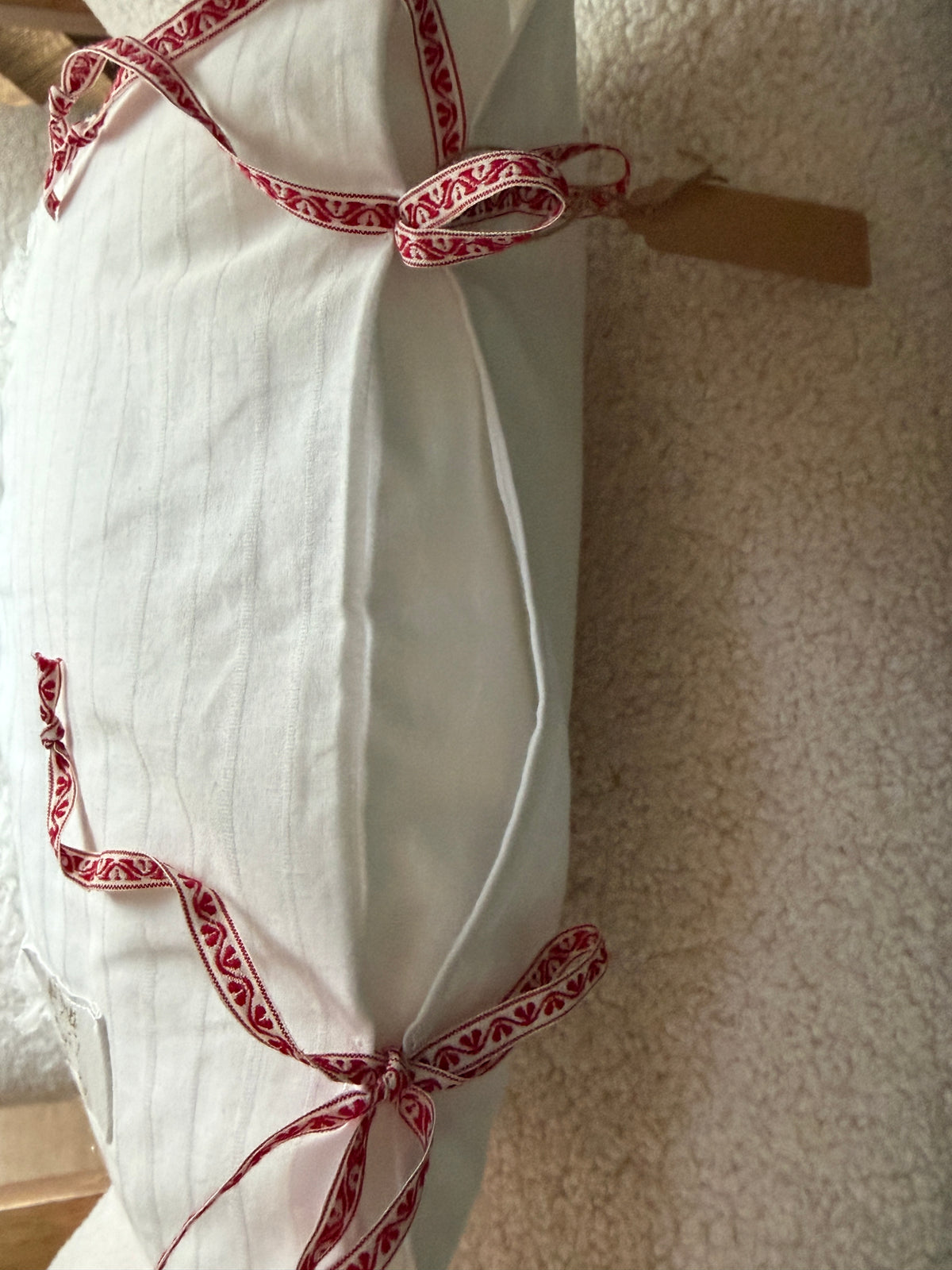 Côté coussin fait main en lin blanc rayé avec noeuds en ruban brodé motif folklorique rouge et blanc