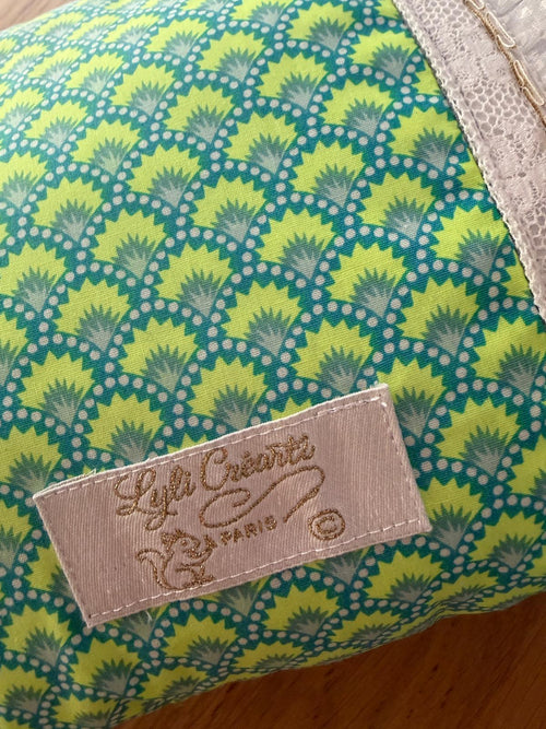 Zoom coussin fait main Lyli Créarti, tissu imprimé écailles vert et bleu, étiquette de marque et bordure en dentelle