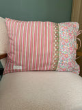 Coussin rectangulaire fait main Lyli Créarti, tissu rayé rose et taupe et imprimé fleuri liberty, galon écaille brodé, posé sur fauteuil en bouclette blanche