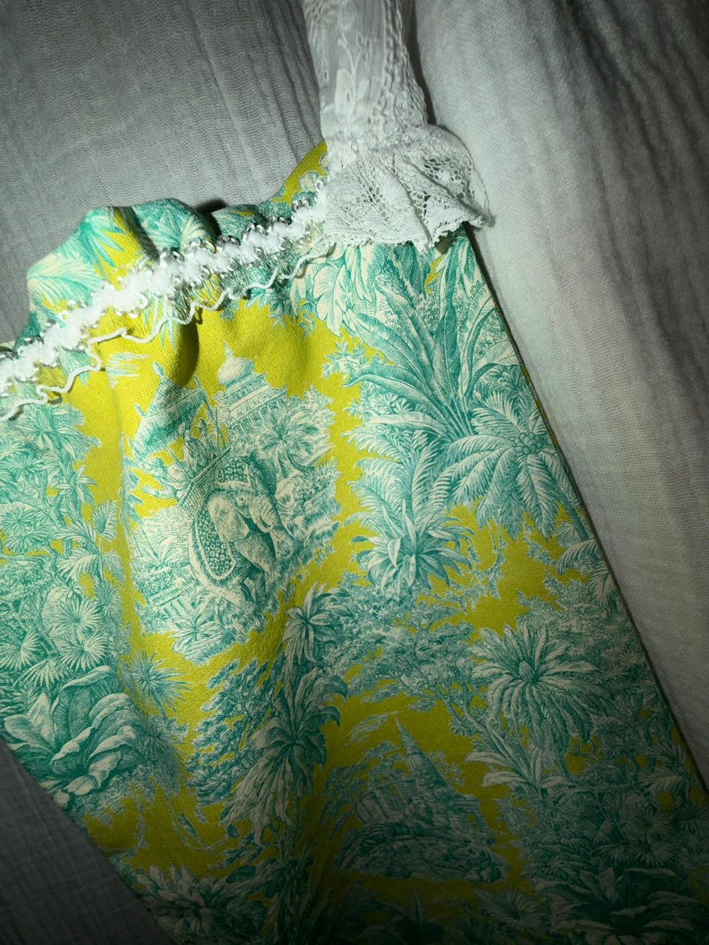 Zoom bourse fait main Lyli Créarti, tissu imprimé toile de Jouy vert et jaune motif éléphants, cordon en dentelle blanche