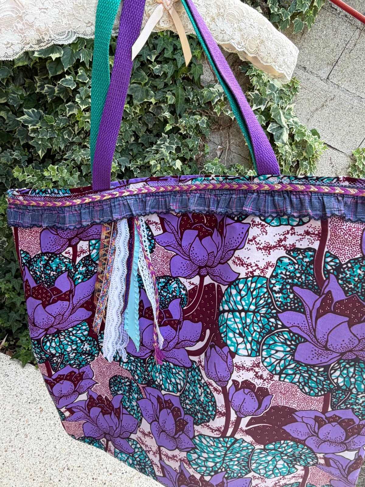 Sac cabas fait main Lyli Créarti, tissu wax imprimé fleurs de lotus violet et turquoise, anses tressées violettes et vertes, volant écossais et rubans en dentelle