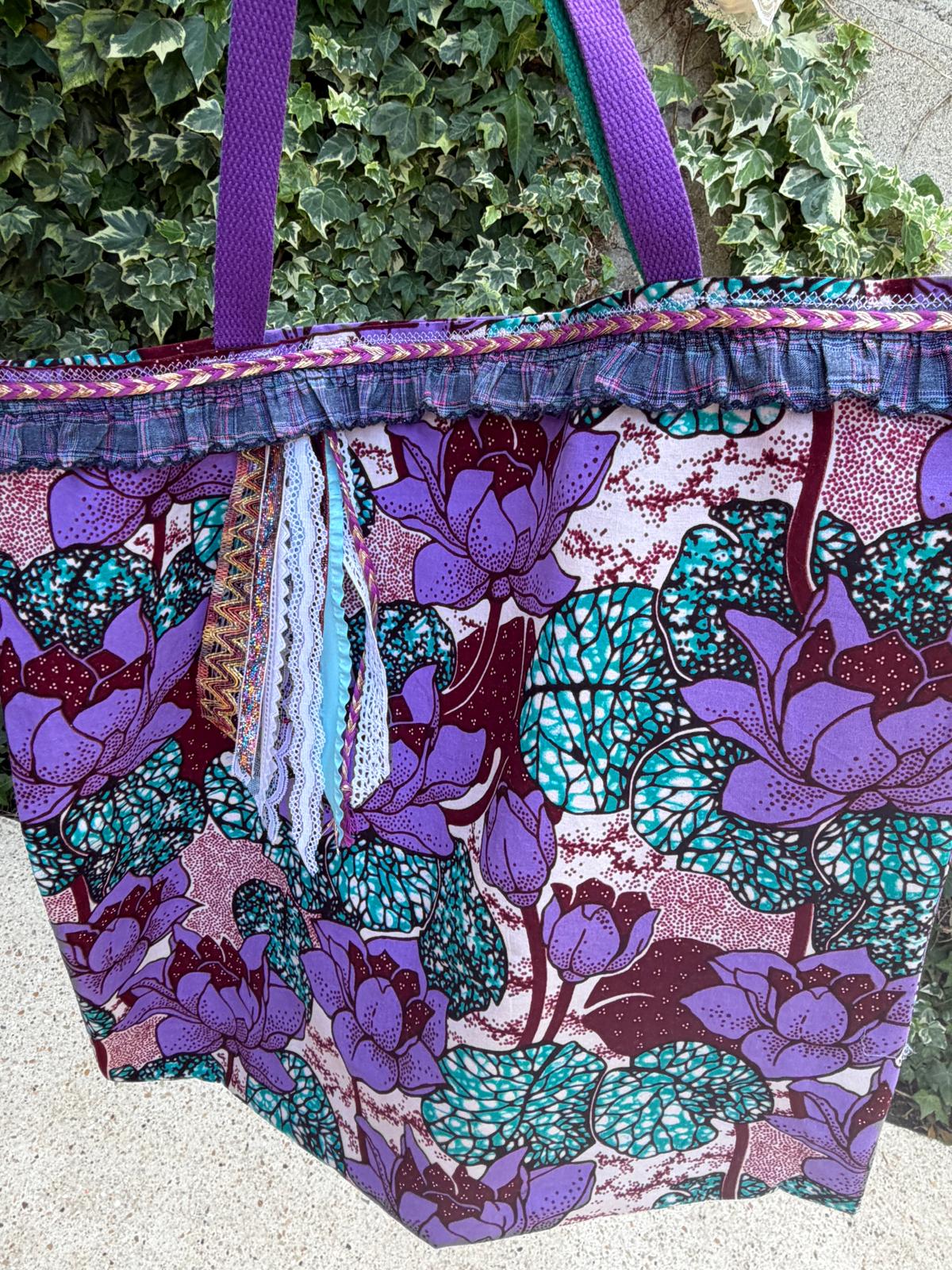 Sac cabas fait main Lyli Créarti en extérieur, tissu wax imprimé fleurs de lotus violet et turquoise, volant écossais et anses tressées violettes