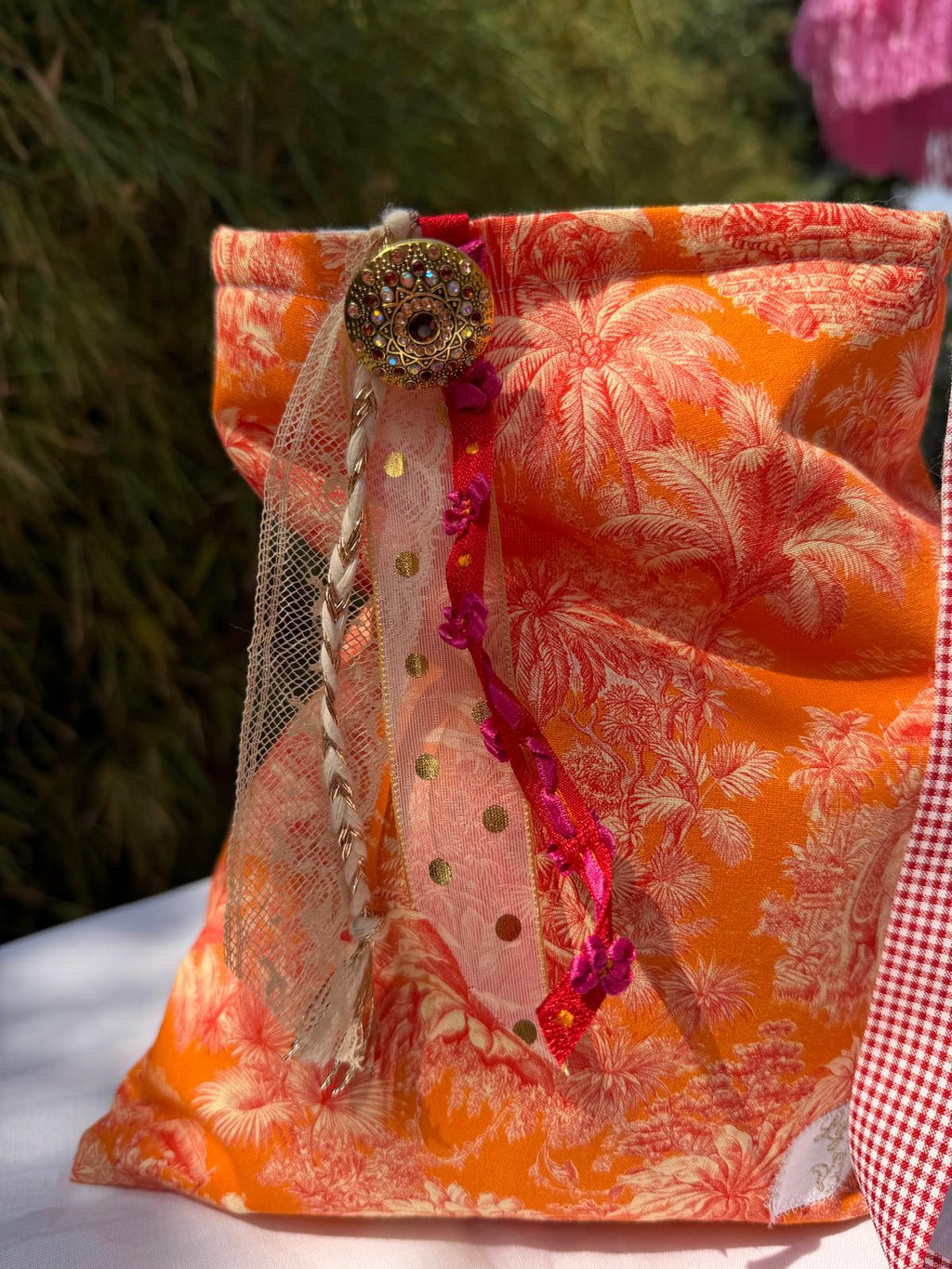 Bourse fait main en tissu imprimé toile de Jouy orange motif palmiers, vue de face avec bouton bijou, rubans en dentelle et tulle doré