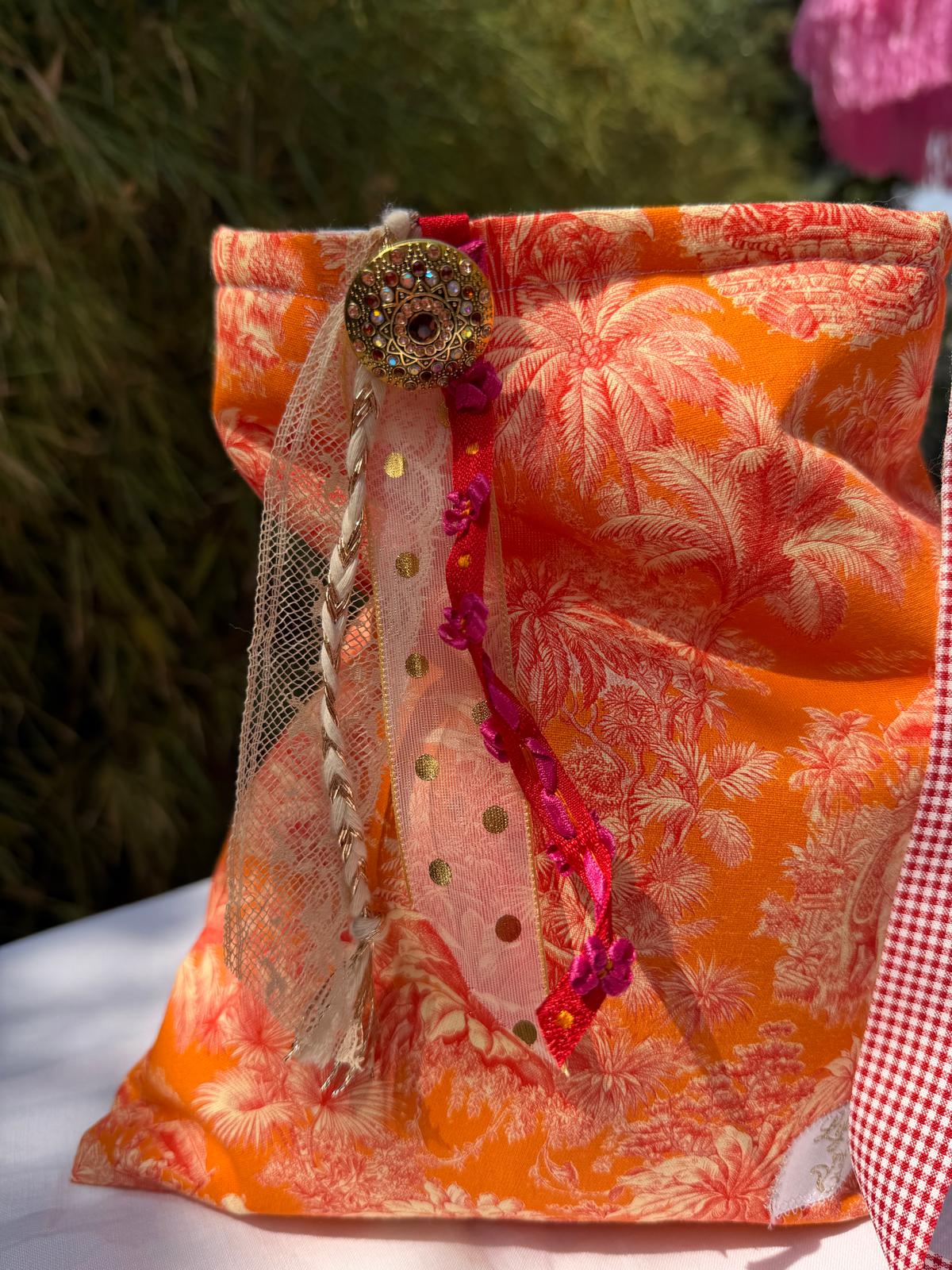 Bourse fait main en tissu imprimé toile de Jouy orange motif palmiers, vue de face avec bouton bijou, rubans en dentelle et tulle doré