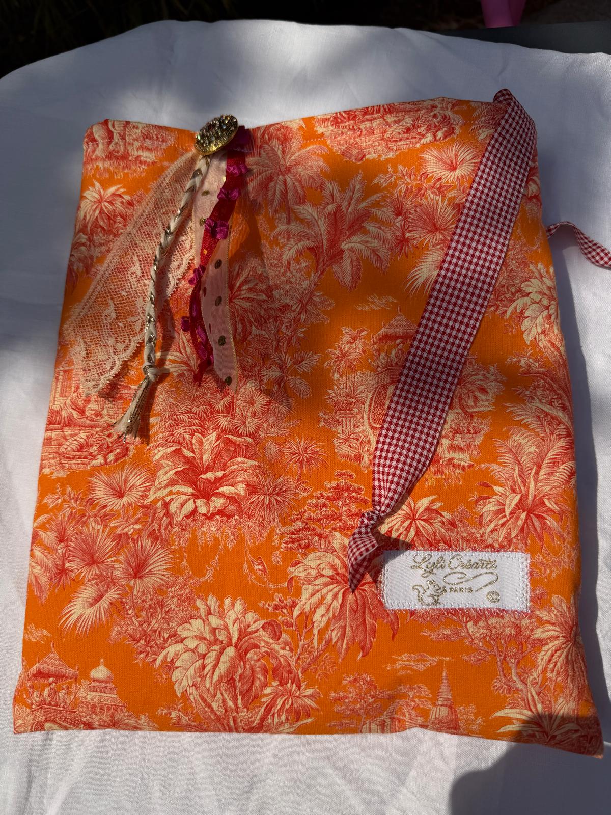 Bourse fait main à plat en tissu toile de Jouy orange motif palmiers, étiquette Lyli Créativ Paris et anse à carreaux vichy rouge et blanc