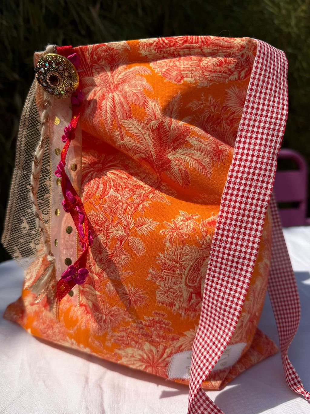 Bourse fait main en tissu imprimé toile de Jouy orange motif palmiers, anse à carreaux vichy rouge et blanc, bouton bijou et rubans en dentelle