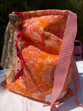Bourse fait main en tissu imprimé toile de Jouy orange motif palmiers, anse à carreaux vichy rouge et blanc, bouton bijou et rubans en dentelle