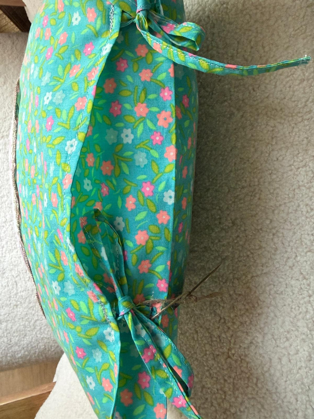 Détail coussin fait main, côté en tissu imprimé fleuri turquoise avec liens noués assortis