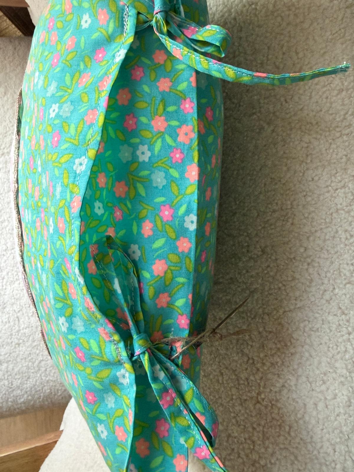 Détail coussin fait main, côté en tissu imprimé fleuri turquoise avec liens noués assortis