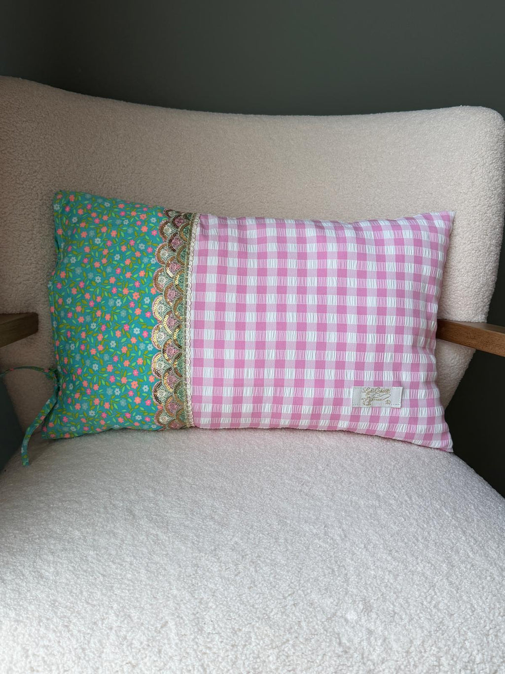 Coussin rectangulaire fait main, tissu vichy rose et blanc et imprimé fleuri vert sur fond turquoise, galon écaille doré, posé sur fauteuil en bouclette blanche