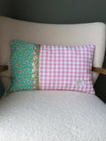 Coussin rectangulaire fait main, tissu vichy rose et blanc et imprimé fleuri vert sur fond turquoise, galon écaille doré, posé sur fauteuil en bouclette blanche