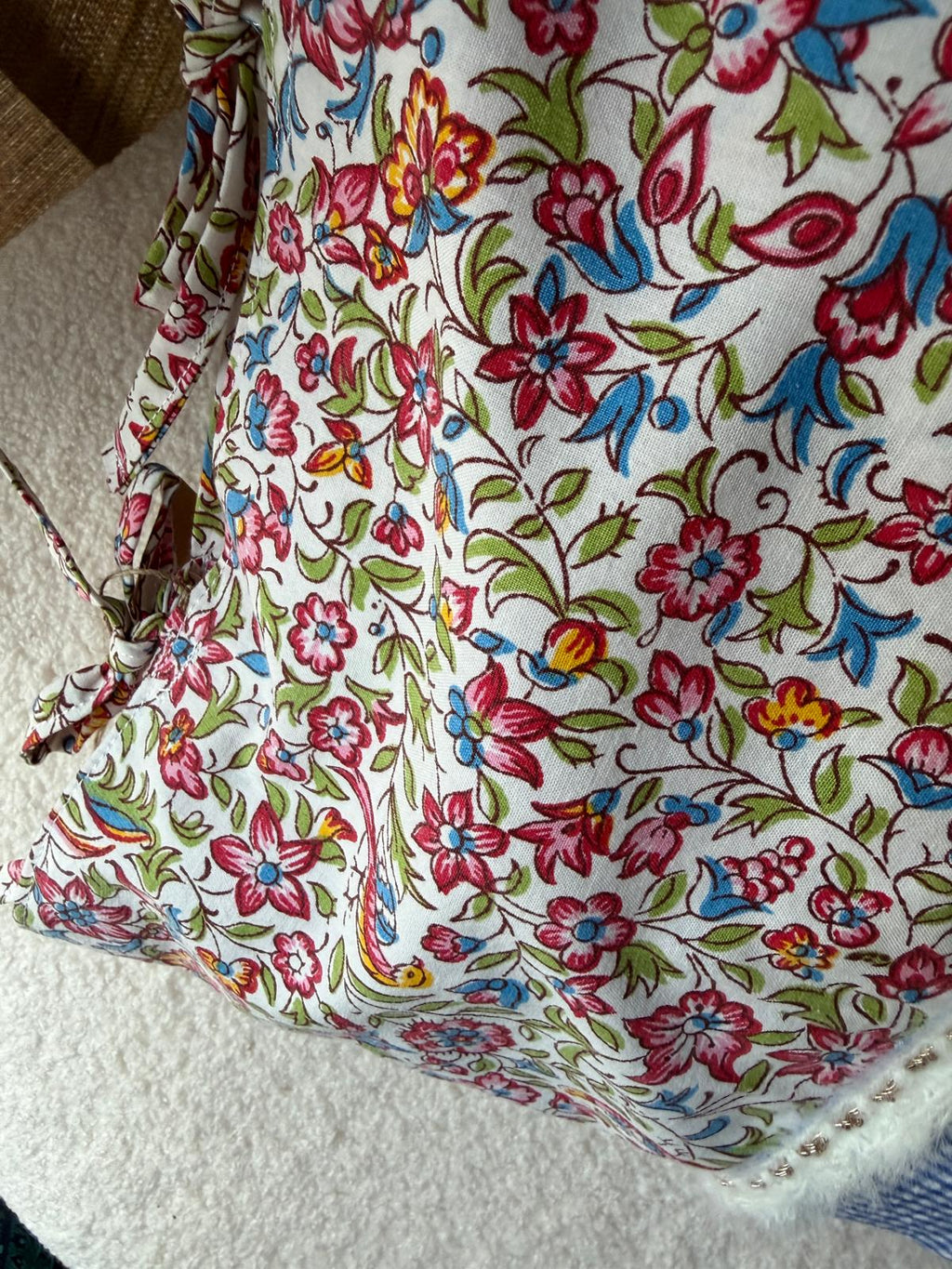 Vue rapprochée coussin fait main, tissu liberty fleuri multicolore avec liseré dentelle