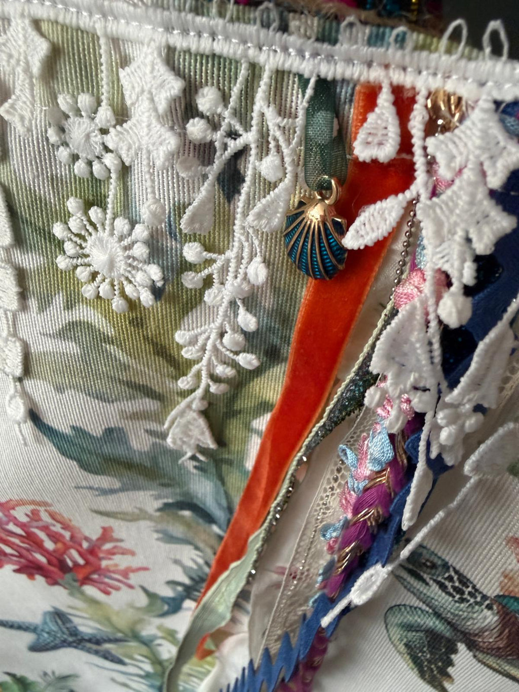 Détail breloque coquillage bleu, ruban de velours orange et dentelle blanche sur sac cabas motif marin