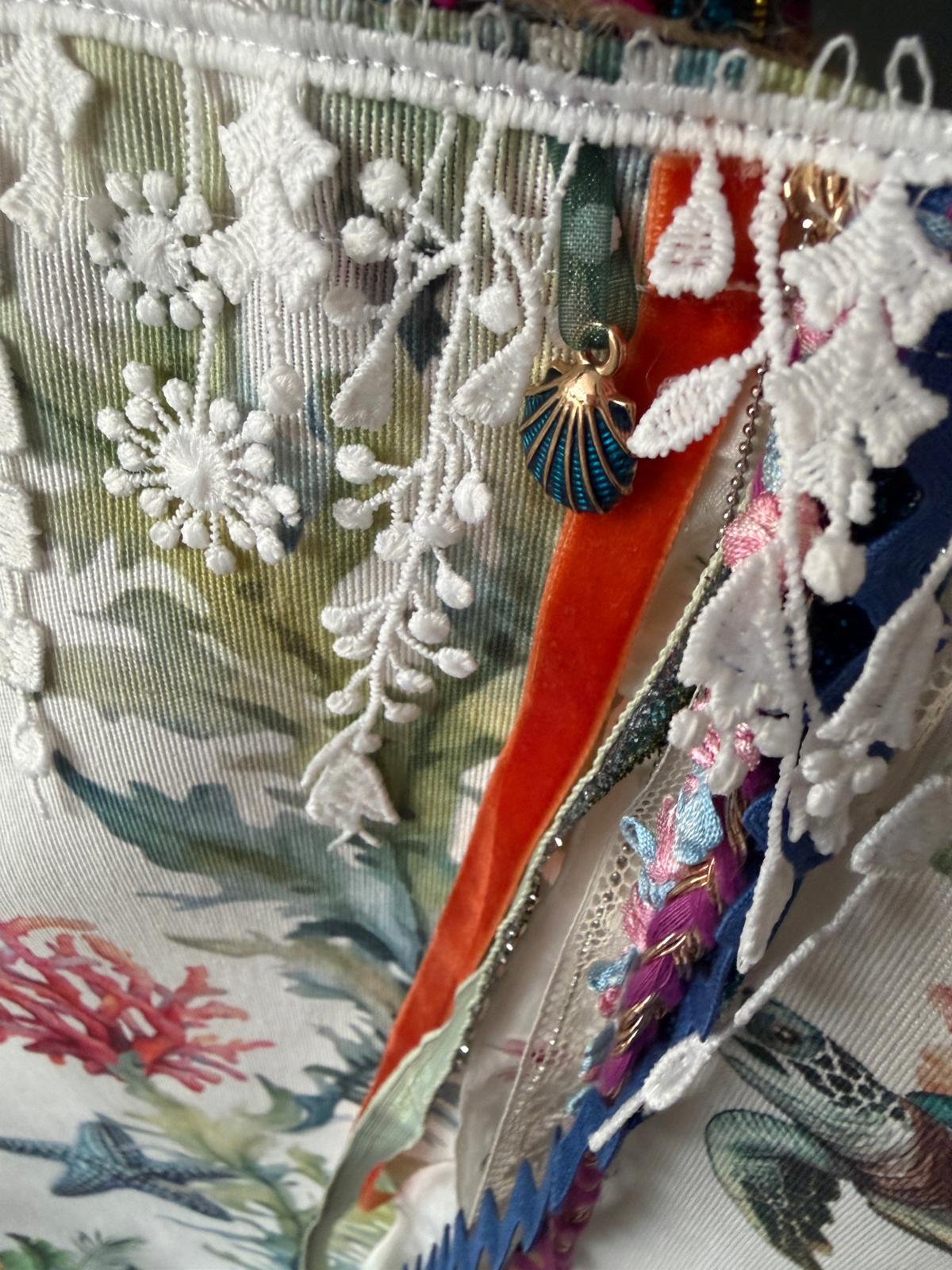Détail breloque coquillage bleu, ruban de velours orange et dentelle blanche sur sac cabas motif marin