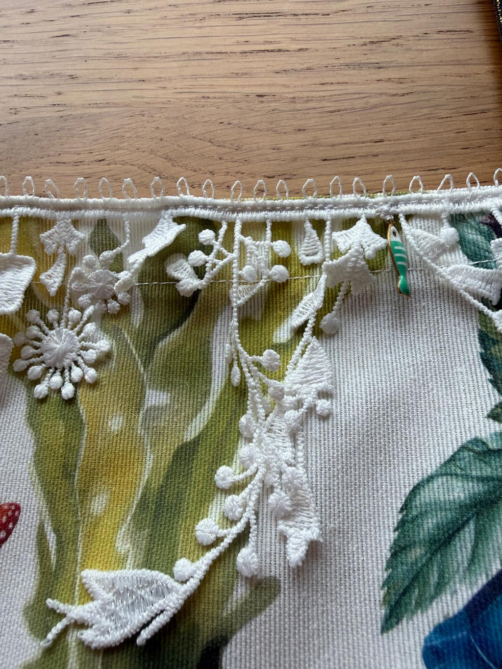 Détail galon de dentelle blanche à motifs floraux et breloque poisson sur sac cabas motif marin